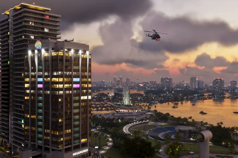 Vista de Vice City al atardecer con rascacielos y un helicóptero